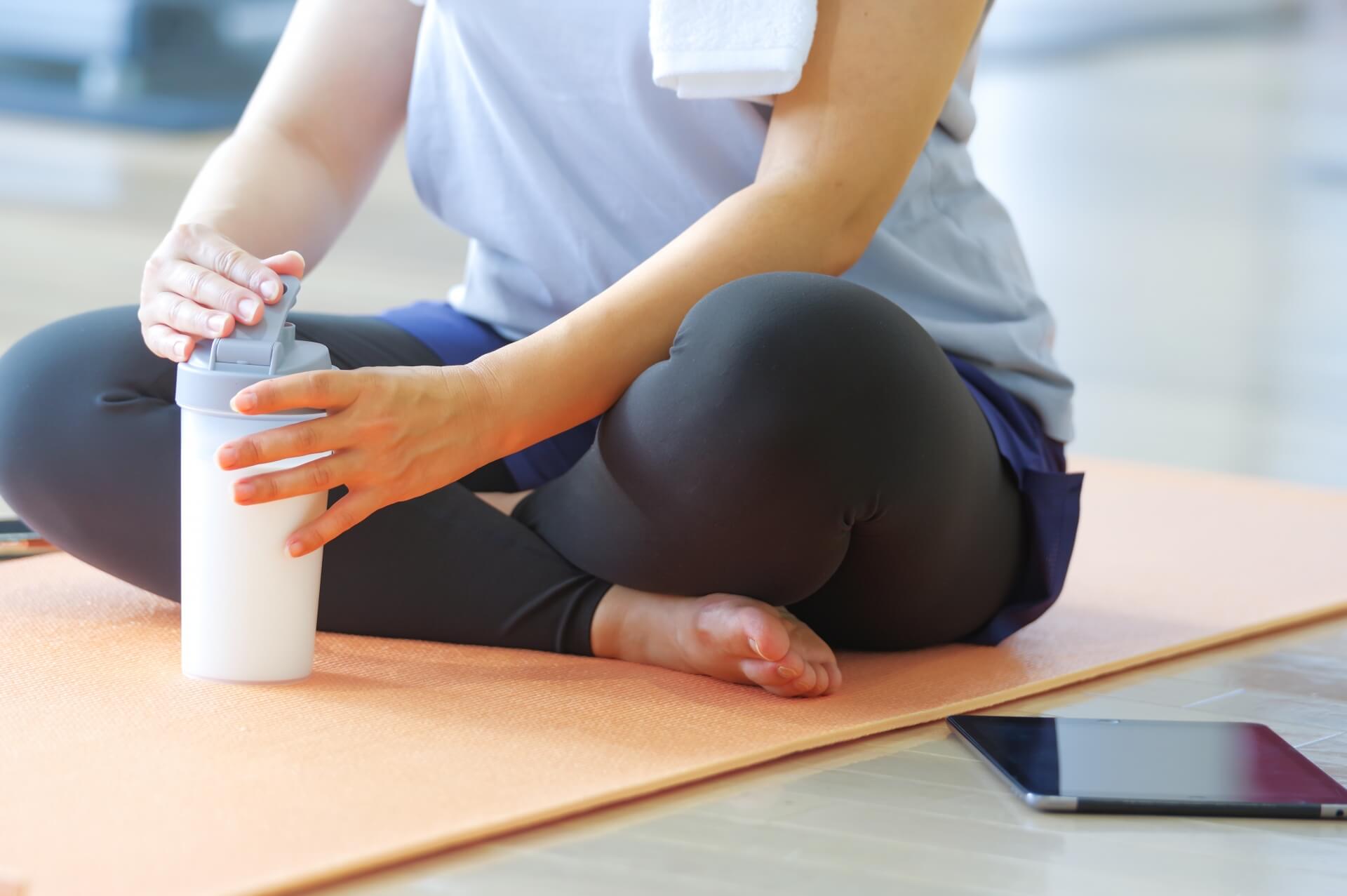 ヨガマットで水を飲む女性